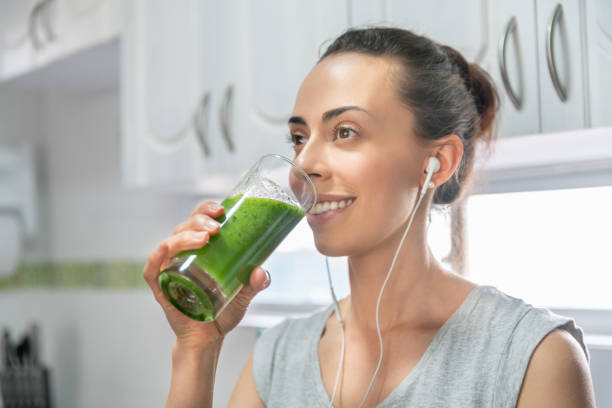 istock Woman drinking a green smoothie at home before her workout 1288162633