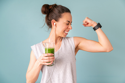 Portrait of a happy Latin American woman drinking a post-workout smoothie to get stronger â healthy lifestyle concepts