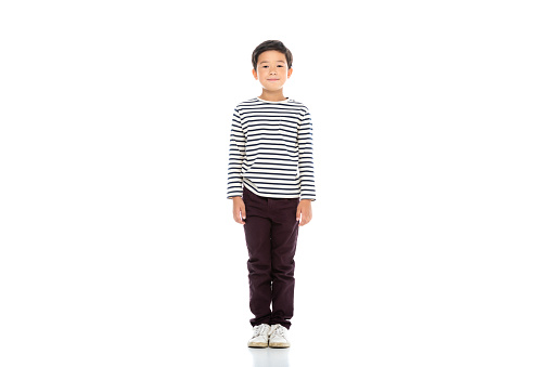 full length of asian boy looking at camera on white background