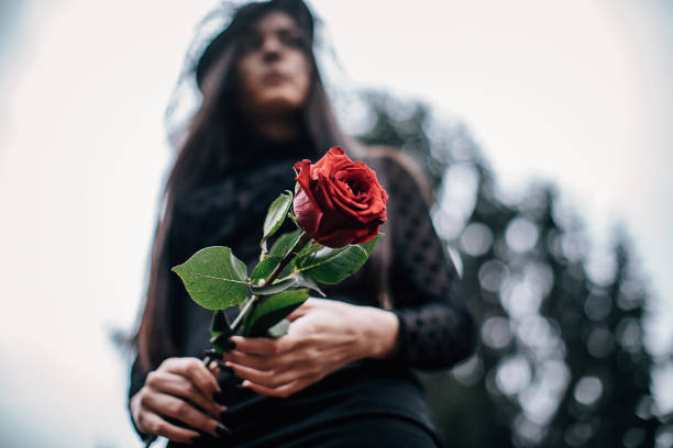 istock One young sad widow carries flowers to a grave 1288165063