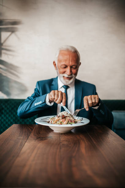 senior affärsman på restaurangbord - cafe buns eating bildbanksfoton och bilder