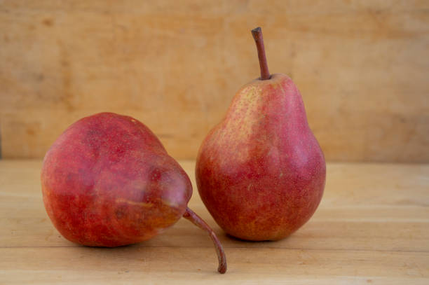 deux poires fruits comestibles, fruit jaune rouge mûri savoureux sur le fond en bois - bartlett pear red pear two objects photos et images de collection