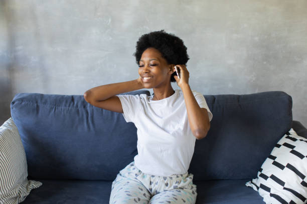 African American girl dancing with her phone on the couch in a cozy room stock photo