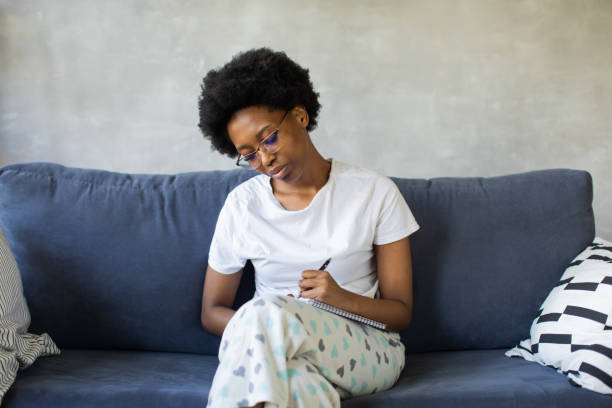 African American girl writes in a notebook in a cozy room stock photo