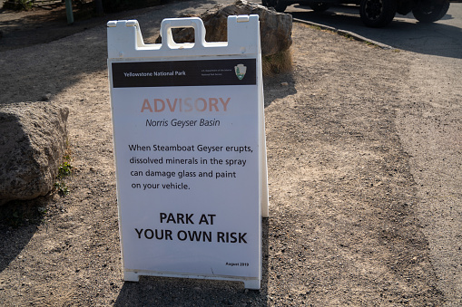 Wyoming, USA - September 23, 2020: Sign warning tourists of the dangers of parking near Steamboat Geyser at Norris Geyser Basin. Damage to cars could happen