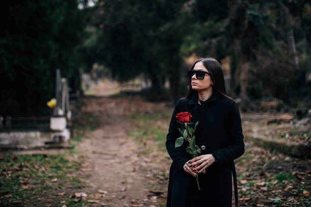 istock Sad widow carries rose flower to a grave 1288172167