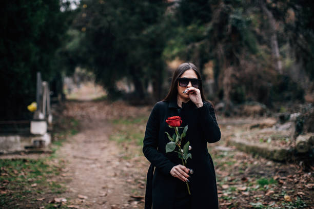 istock One sad widow carries rose flower to a grave 1288172757