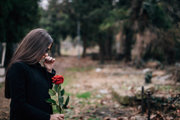 la jeune femme pleure dans un cimetière retenant la rose - veuve photos et images de collection