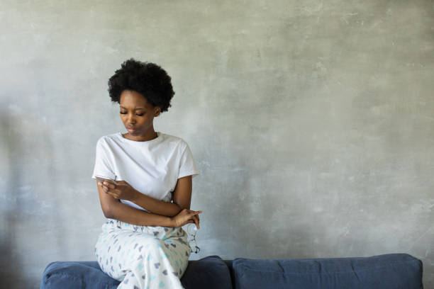 Afro american woman with thoughtful face sitting on couch stock photo