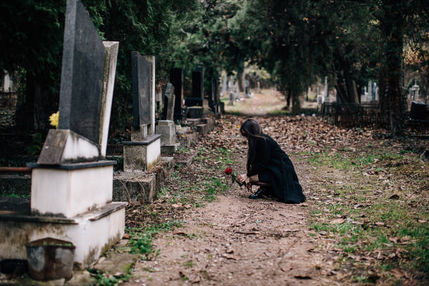 istock One sad young widow places rose flower on the grave 1288174743