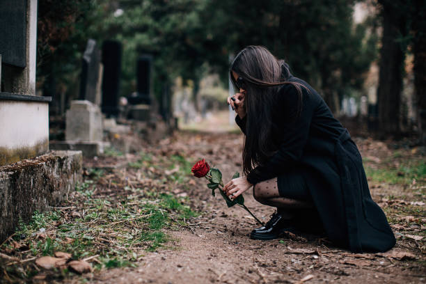 istock Sad young widow places rose flower on the grave 1288174795