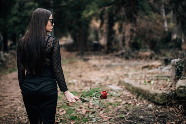 istock One sad young widow carries rose flower to a grave 1288175674