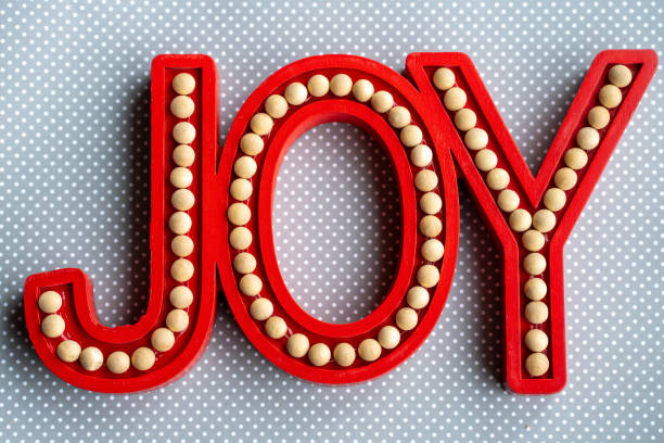 istock Red Joy word letters on a gray white polka dot wood background, useful for rustic Christmas holiday projects 1288177182