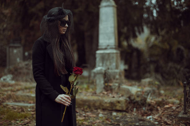 istock Young widow carries flowers to a grave in a cemetery 1288180902