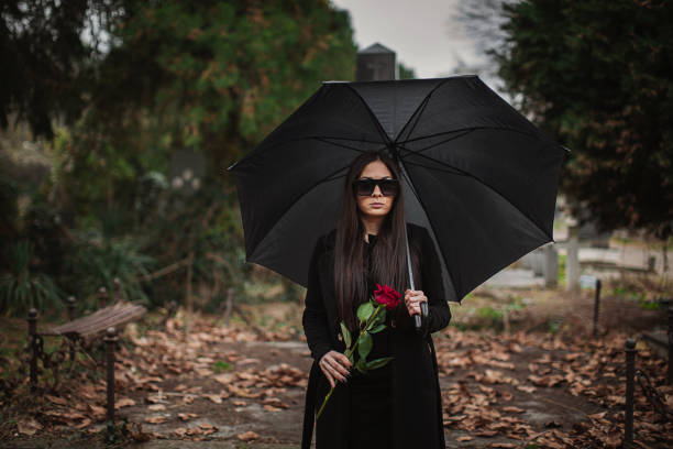 грустная молодая вдова несет цветы к могиле на кладбище - widows walk стоковые фото и изображения