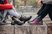 Couple in modern boots sitting outdoors in city