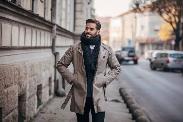 One young handsome man dressed in warm winter clothing walking on the city street.