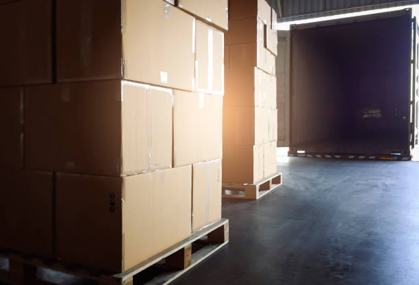 istock Cargo shipment boxes, Freight truck, Warehousing. Stack of cardboard boxes on pallet waiting to load into shipping cargo container. 1288194502