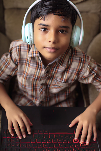 Portrait of Indian little boy using laptop while attending the online class at home