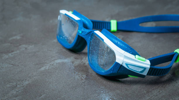 istock Wet blue men's swimming goggles on a stone background. 1288200943