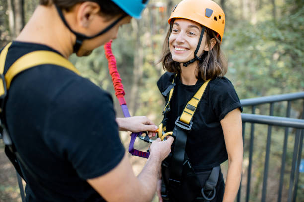 Rope park worker wearing safety equipment on a woman Rope park worker wearing safety equipment on a woman for a bungee jump bungee jumping stock pictures, royalty-free photos & images