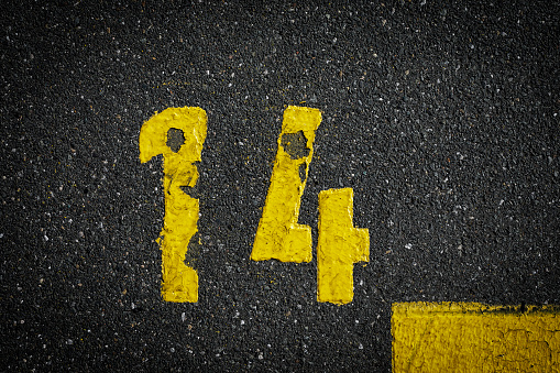 sign on the asphalt, yellow painted number fourteen on grey street, yellow lines like a corner on the road, space for text