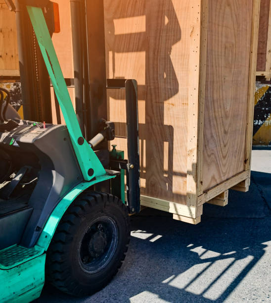 istock Worker driving forklift loading shipment carton boxes goods on wooden pallet at loading dock from container truck to warehouse cargo storage in freight logistics, transportation industrial, delivery 1288207570