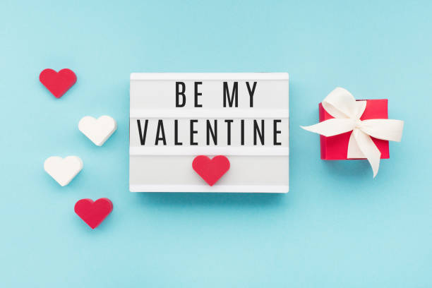 istock Text Be My Valentine on white lightbox. Red gift box, hearts on pastel blue background. Valentines day concept. 1288218052