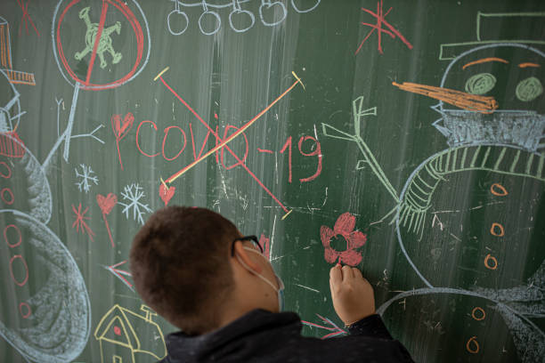 istock A boy with mask draws with chalk on a blackboard 1288218766