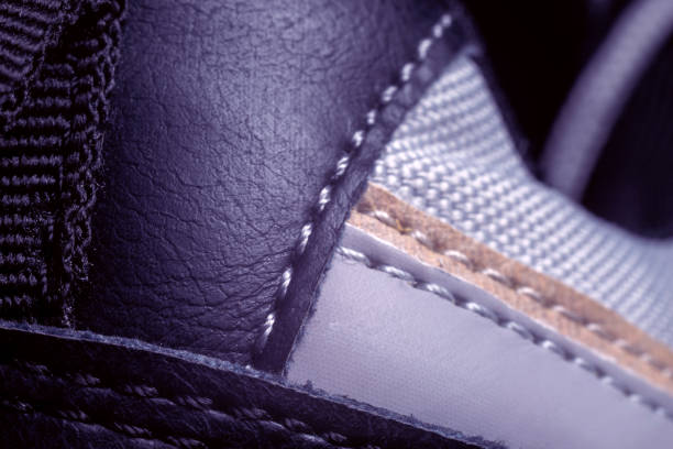 This close-up captures the intricate detail of a shoe's materials, highlighting the contrasting textures of leather and suede along with precise stitching against a muted background.