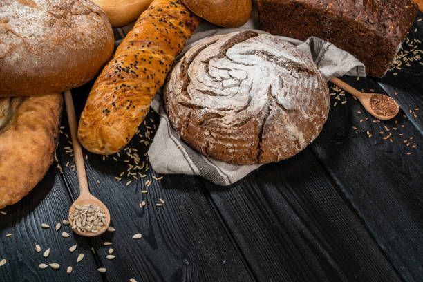 istock Rustic bread and wheat on an old vintage planked wood table. Dark moody background with free text space 1288219980