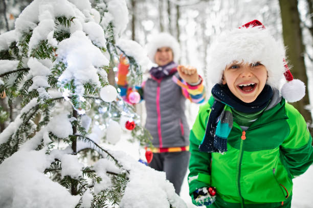 Kids decorating Christmas tree outdoors