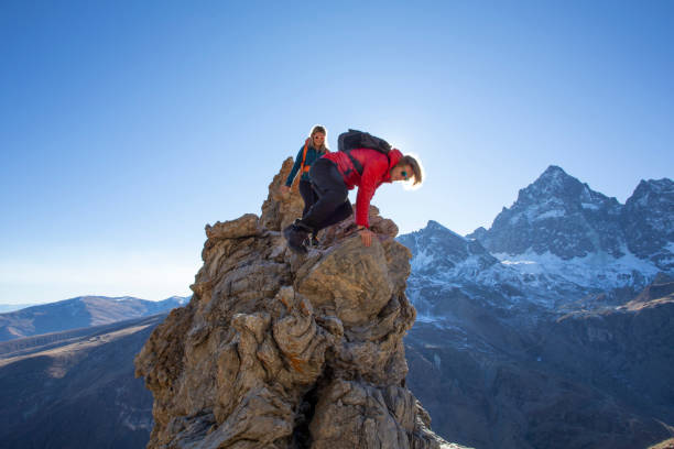 istock Hikers scramble down sunny mountain pinnacle in the morning 1288229934