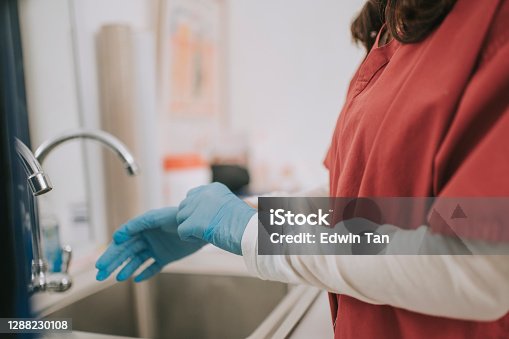 istock asian chinese dentist with medical scrub wearing surgical glove getting ready for surgery at dentist office 1288230108
