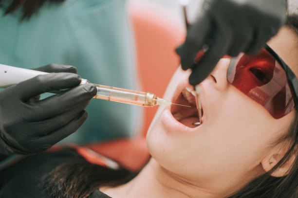 asian chinese female dentist giving injection on patient tooth asian chinese female dentist giving injection on patient tooth surgical light stock pictures, royalty-free photos & images