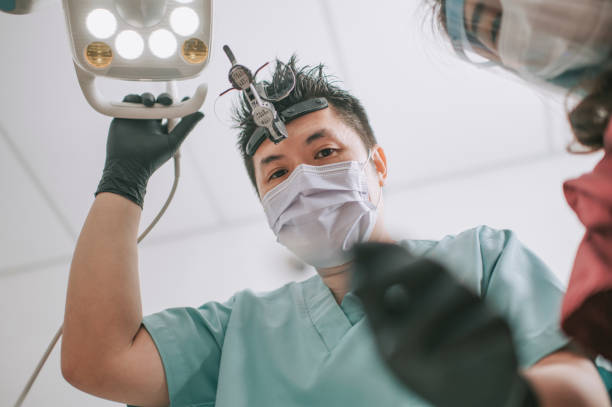 아시아 중국 남성 치과 의사 내도증 과 돋보기 안경 과 빛 에서 위에서 찾고 환자 - dental equipment dental drill dentist surgical mask 뉴스 사진 이미지