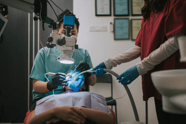 istock Asian chinese male dentist looking through microscope on patient's teeth in dentist's office Root canal treatment 1288230322