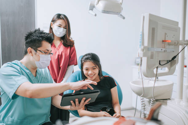 asiatische chinesische männliche zahnarzt erklärt zahn-röntgen strahlen an einen patienten - künstliches gebiss fotos stock-fotos und bilder