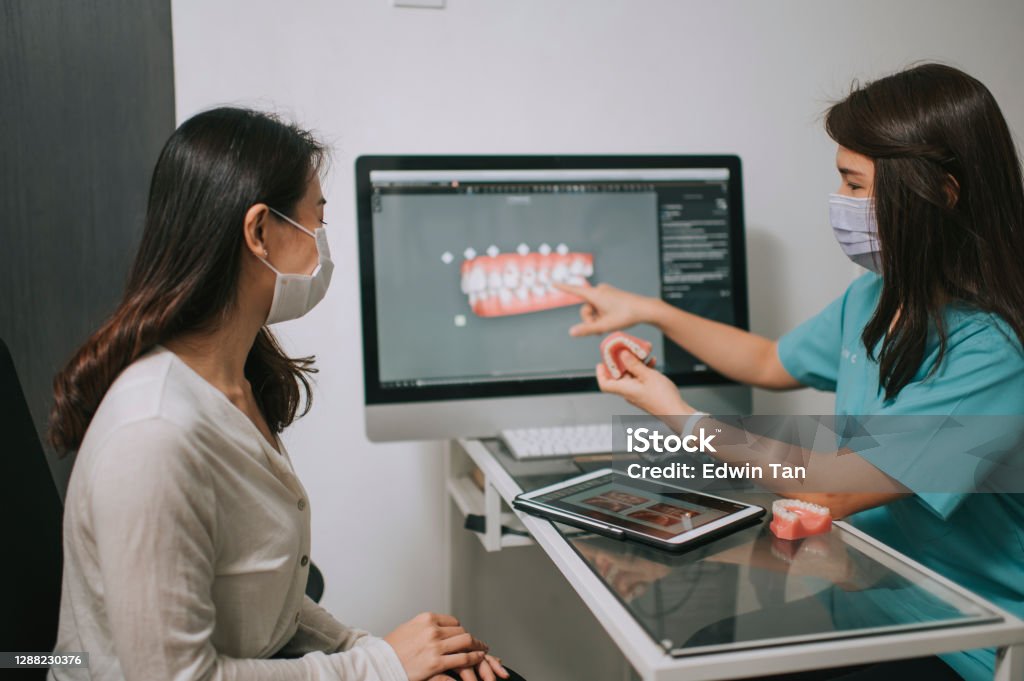 asian chinese female dentist explaining Tooth3D To A Patient asian chinese female dentist explaining Tooth X-Rays To A Patient Dentist Stock Photo