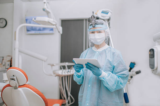 istock asian chinese dentist with PPE protective workwear holding digital tablet in dentist's office looking at camera 1288230435