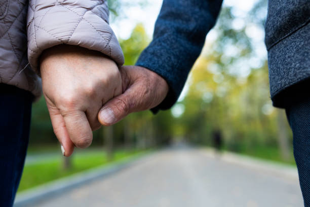 istock Unrecognizable man and woman holding hands while standing on path during date in park 1288236821