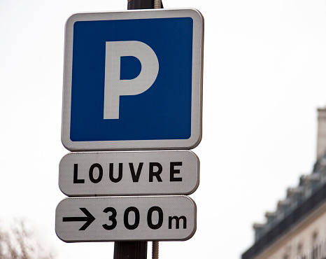 Parking road sign and signpost from the distance to the Louvre in Paris. Information about the distance to the Louvre palace museum complex in the capital of France.