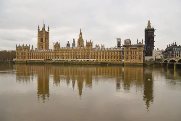 London, United Kingdom - November 2020: Daytime view of Palace of Westminster and Big Ben reflected in the Thames.