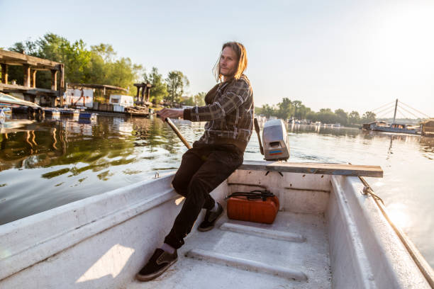 istock Man in old white boat is rowing in sunrise 1288242103