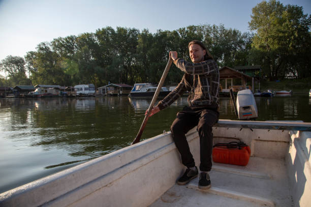 istock Man in old white boat is rowing in sunrise 1288242127