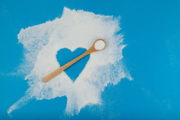 istock Collagen powder or protein is chaotically scattered on blue surface. Empty space in the form of heart. Bamboo spoon imitates an arrow. Healthy food Supplement 1288243598
