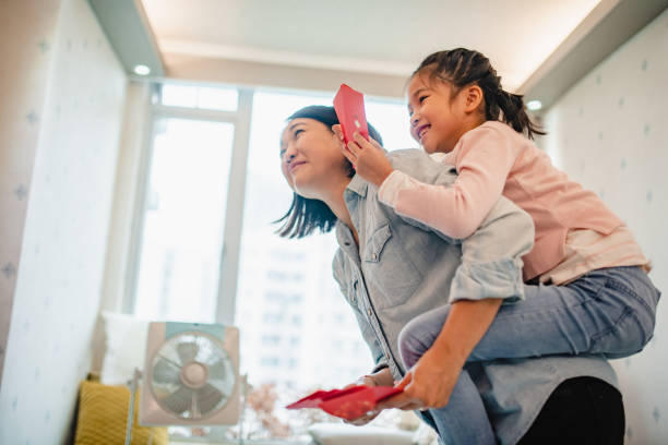 Mature woman carrying 6 year old child piggyback and holding traditional monetary gift packets that symbolize good luck and are given out on special occasions.
