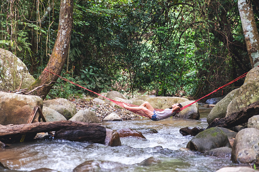 A woman sleeping and relaxing in hammock in waterfall stream