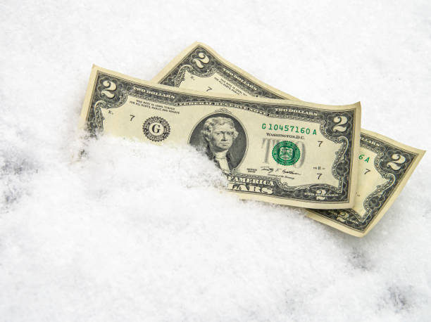 istock US dollar in the snow. Two dollar bills. Financial concept. 1288248805