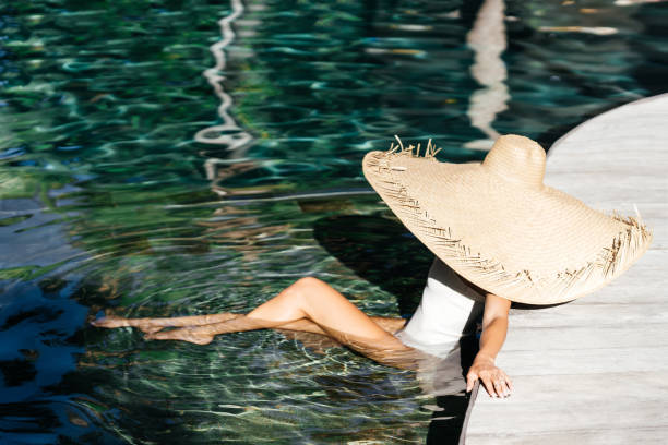 istock Woman in big straw hat relaxing at pool. 1288248891